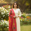 Woman in cream Indian ethnic wear with red embroidered dupatta standing in garden with flowers