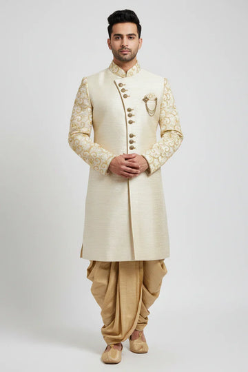 Man wearing cream and gold embroidered Indian sherwani with matching dhoti pants and traditional juttis