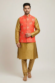 Man wearing golden silk kurta pajama with a coral orange floral Nehru jacket, ethnic Indian attire from Anandi Fashions