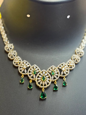 Elegant Indian ethnic necklace with gold, diamond accents, and green emerald teardrop gemstones on black display