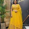 Woman wearing yellow embroidered Indian lehenga with floral details and matching dupatta at Anandi Fashions studio
