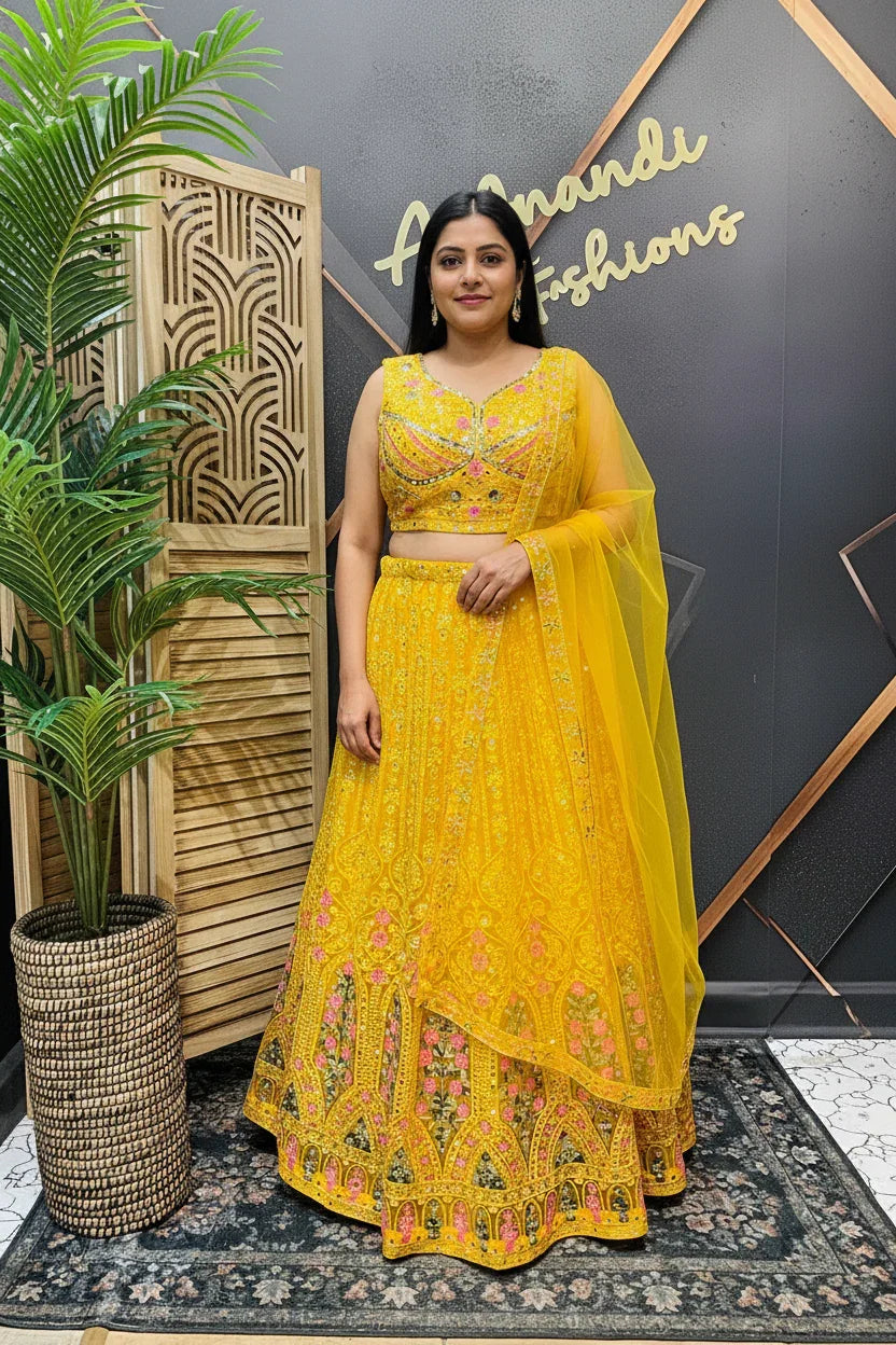 Woman wearing yellow embroidered Indian lehenga with floral details and matching dupatta at Anandi Fashions studio