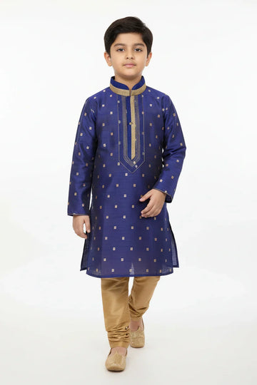 Boy in blue embroidered kurta with gold churidar pants and traditional Indian footwear on white background