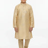 Boy wearing gold embroidered kurta set with churidar and brown sandals against white background