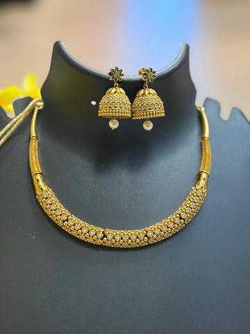 Gold-tone Indian ethnic jewelry set with stone-studded necklace and matching jhumka earrings on black display