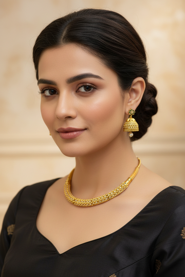 Close-up of a woman wearing elegant gold necklace and jhumka earrings with black ethnic dress at Anandi Fashions