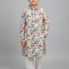 Boy wearing multicolor floral print kurta and white churidar pants on gray background