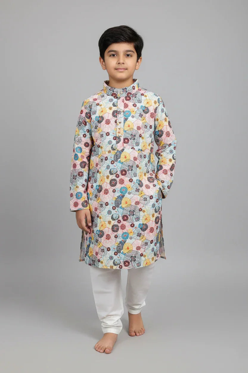 Boy wearing multicolor floral print kurta and white churidar pants on gray background