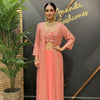 Woman in pink Indian ethnic outfit with sequined long jacket, crop top, jewelry, standing by plant at Anandi Fashions