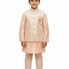 Smiling boy in peach Indian ethnic kurta with embroidered sleeveless jacket, standing barefoot