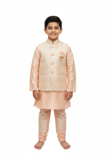 Smiling boy in peach Indian ethnic kurta with embroidered sleeveless jacket, standing barefoot