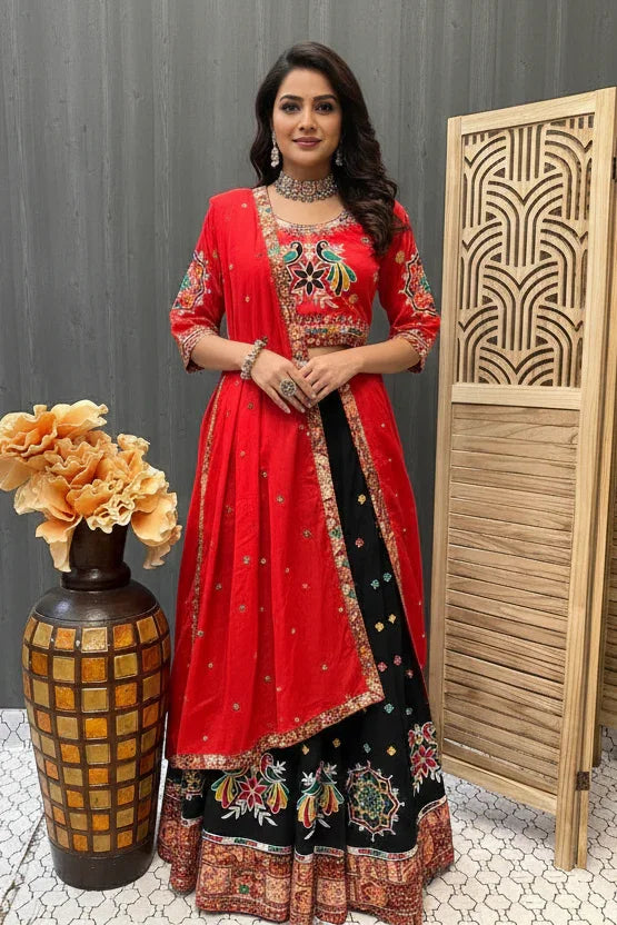 Woman in a red and black traditional outfit standing next to a decorative vase and wooden screen.