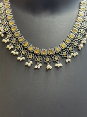 Traditional Indian oxidized silver necklace with yellow stones, floral motifs, and pearl danglers on black background