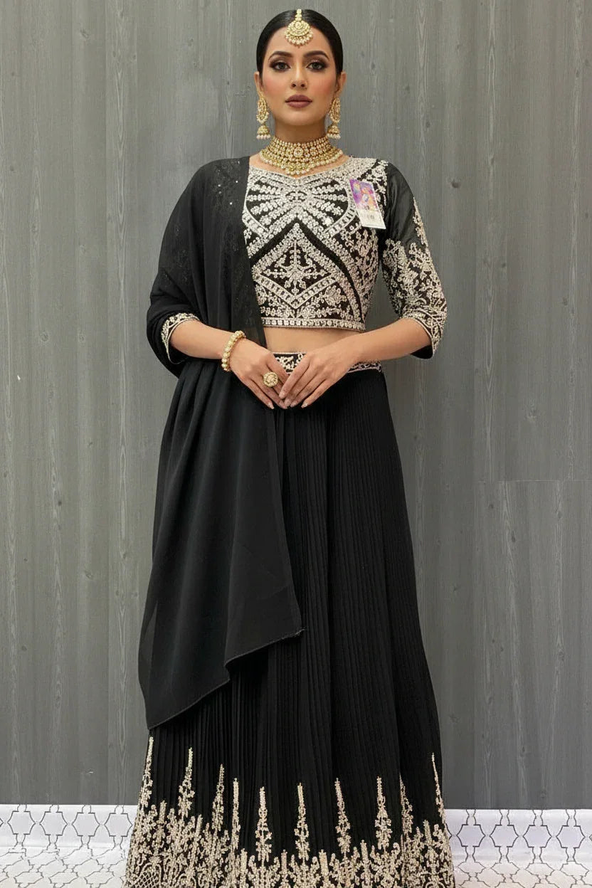 Woman modeling black Indian ethnic lehenga with silver embroidery, matching dupatta, and traditional gold jewelry at Anandi Fashions