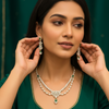 Woman in green ethnic wear wearing matching diamond and emerald necklace and earrings jewelry set