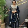 Woman in navy blue embroidered traditional Indian lehenga and dupatta standing indoors at Anandi Fashions boutique