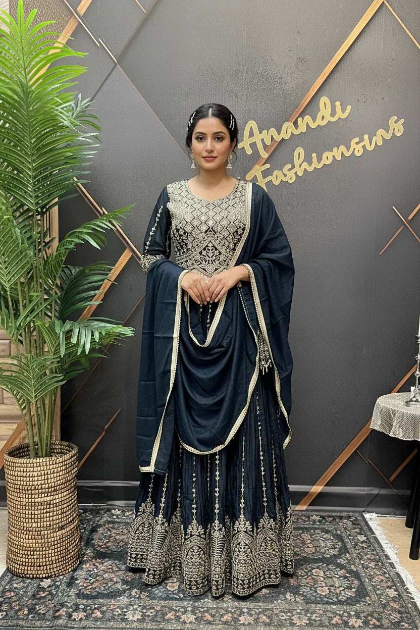 Woman in navy blue embroidered traditional Indian lehenga and dupatta standing indoors at Anandi Fashions boutique