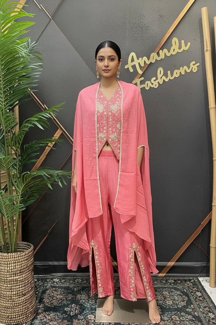 Woman in pink ethnic outfit with embroidered vest and draped cape, standing at Anandi Fashions showroom