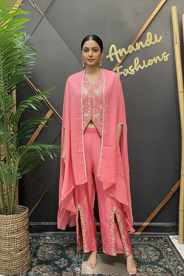 Woman in pink ethnic outfit with embroidered vest and draped cape, standing at Anandi Fashions showroom