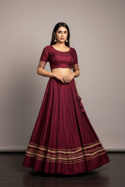 Woman wearing a maroon traditional outfit with a plain background