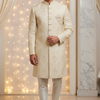 Man wearing a cream sherwani with a decorative background