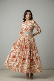 Woman wearing cream and rust floral print long ethnic dress with silver embellished belt and jhumka earrings