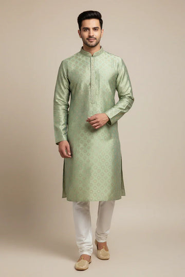 Man wearing light green embroidered Indian ethnic kurta with white churidar and traditional jutti shoes