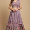 Woman wearing lavender pink heavily embroidered Indian lehenga with floral designs, paired with matching dupatta and traditional jewelry