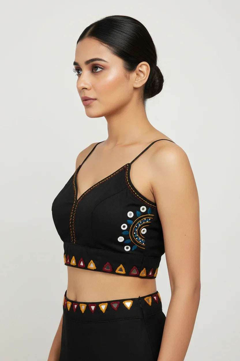 Side view of woman in black ethnic crop top with multicolor embroidery and matching high-waist skirt