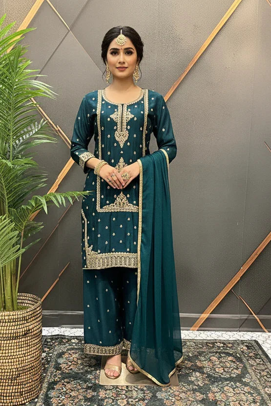 Woman wearing teal Indian ethnic wear with gold embroidery, matching dupatta, and traditional jewelry indoors