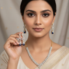 Close-up of woman in beige saree wearing and holding diamond and sapphire Indian ethnic jewelry necklace and earrings