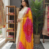 Woman in a cream Indian ethnic kurta with a vibrant pink and yellow bandhani dupatta, standing in a boutique with ethnic wear and decor