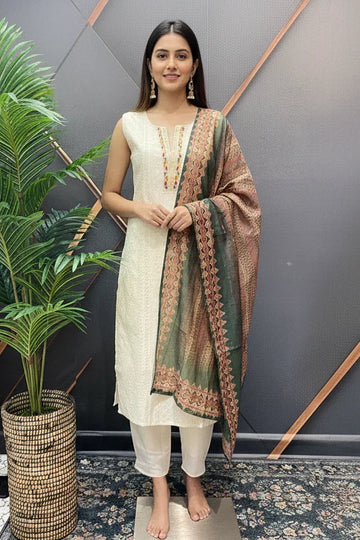 Woman in elegant cream Indian ethnic kurta with multi-colored printed dupatta, standing indoors near plant