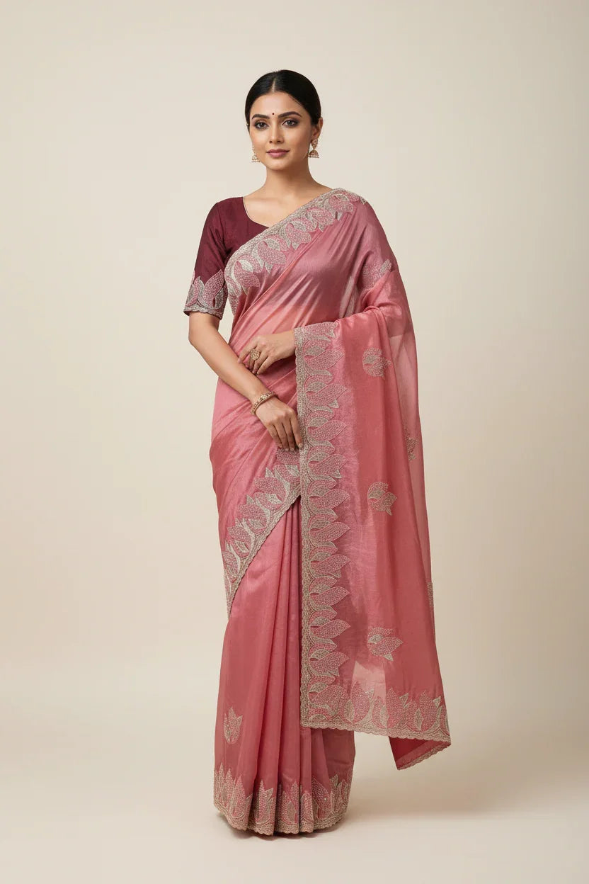 Woman wearing a pink saree with a white border on a beige background