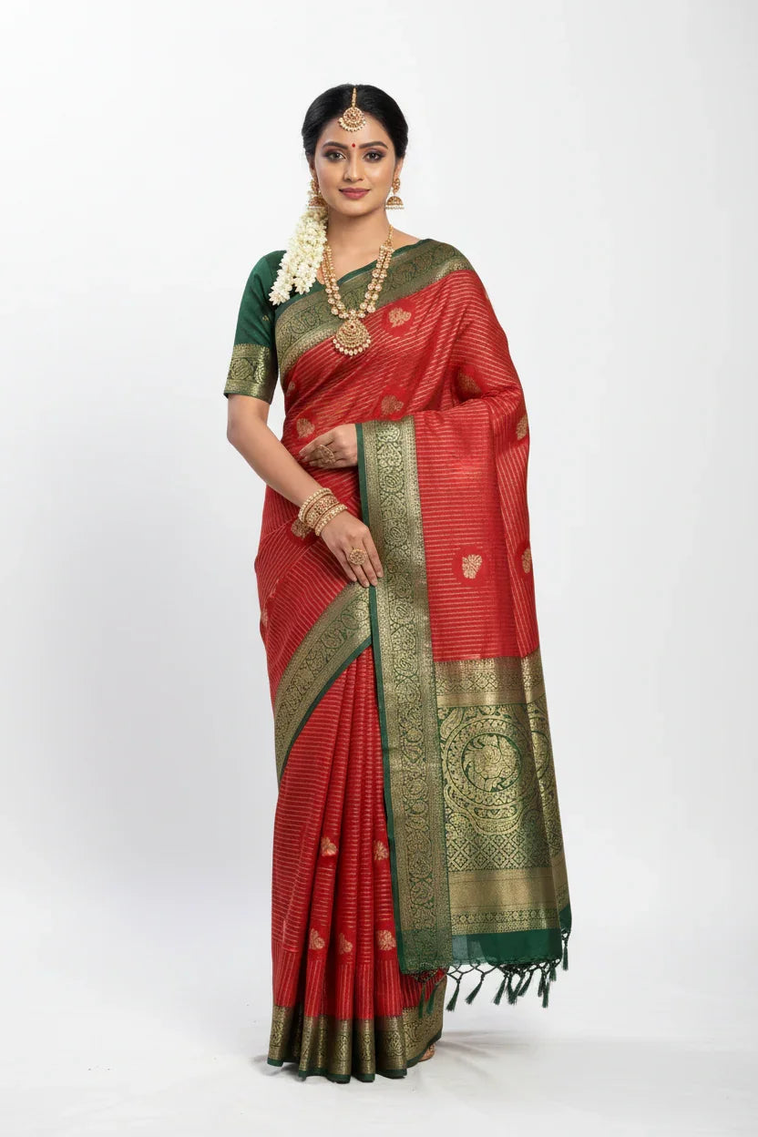Woman wearing traditional red and green silk saree with gold zari work and jewelry at Anandi Fashions