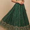 Indian ethnic lehenga with gold embroidered green skirt and gold brocade blouse on model
