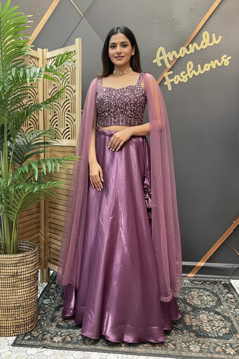Woman wearing a glittery purple lehenga with a matching sheer dupatta standing inside Anandi Fashions boutique