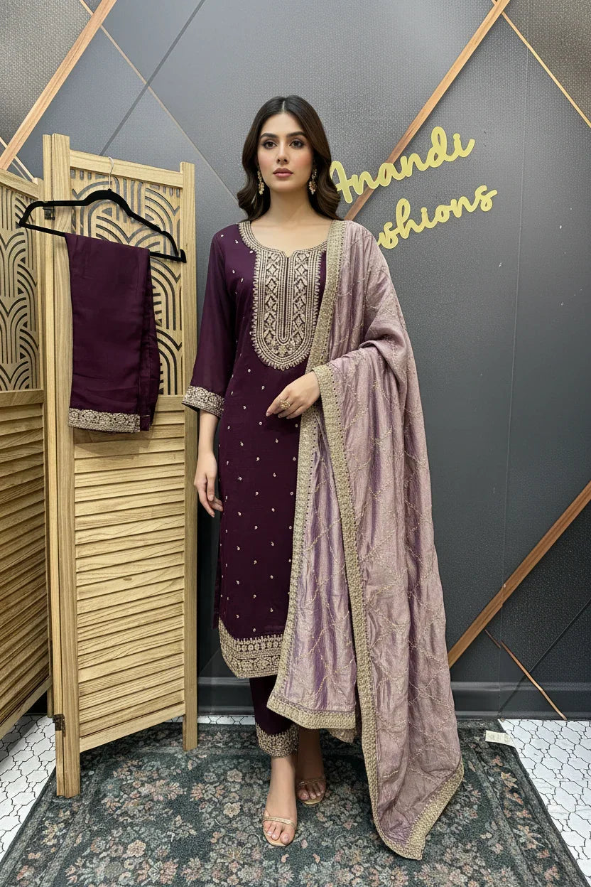 Woman modeling a premium maroon Indian ethnic suit with intricate gold embroidery and a lavender dupatta at Anandi Fashions