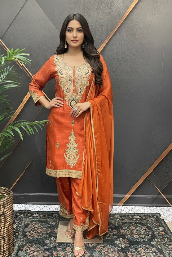 Woman in orange Indian ethnic wear with gold embroidery, matching dupatta, and pants at Anandi Fashions