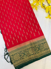 Red Indian ethnic saree with gold zari motifs and green floral embroidered border, styled with yellow flowers