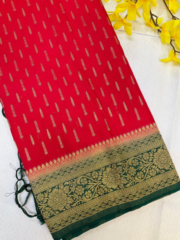 Red Indian ethnic saree with gold zari motifs and green floral embroidered border, styled with yellow flowers