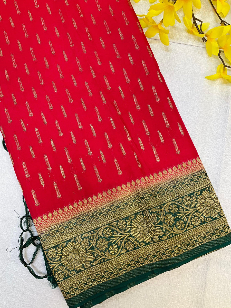 Red Indian ethnic saree with gold zari motifs and green floral embroidered border, styled with yellow flowers