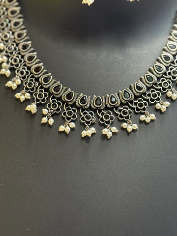 Intricate Indian oxidized silver necklace with black teardrop stones, floral motifs, and pearl dangles