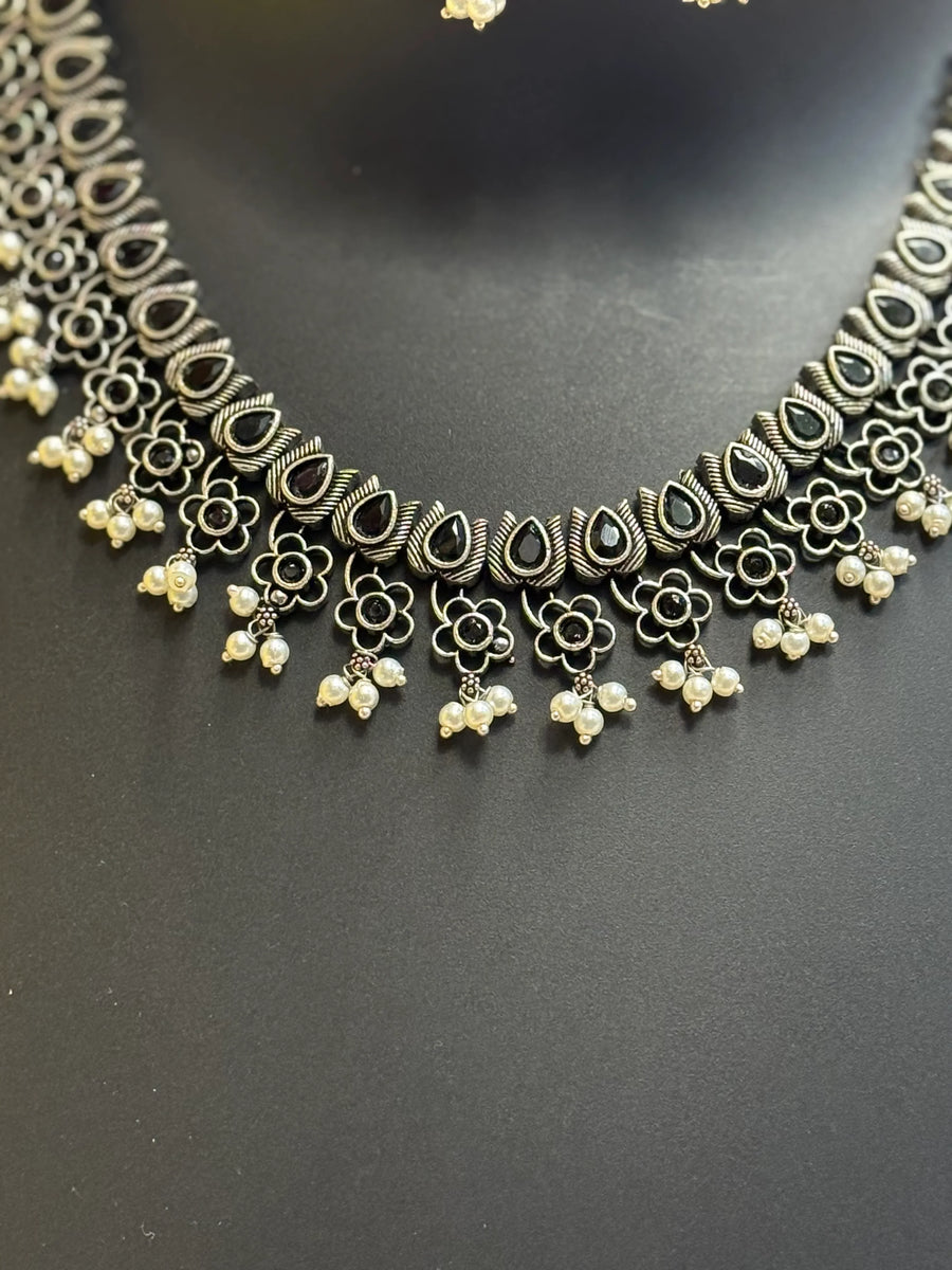 Intricate Indian oxidized silver necklace with black teardrop stones, floral motifs, and pearl dangles