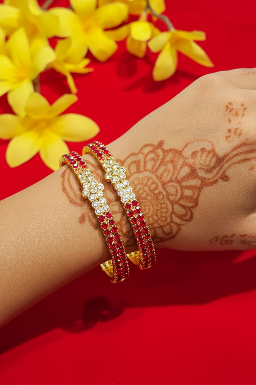 Hand with intricate mehndi design wearing gold-tone bangles with red and white stones on red background with yellow flowers