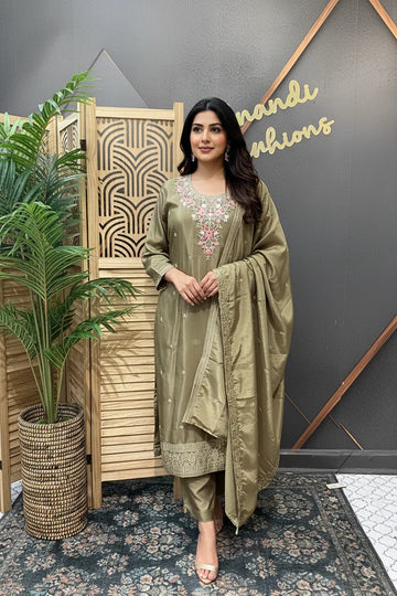 Woman in olive green Indian ethnic wear with floral embroidery, standing indoors at Anandi Fashions store
