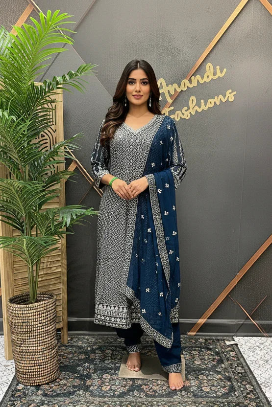 Woman in a blue and silver traditional outfit standing in front of a decorative wall with 'Friends Fashions' branding.