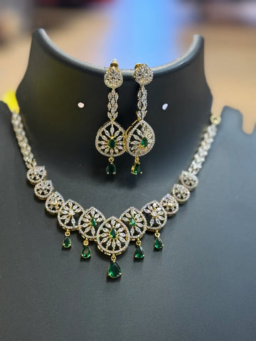 Elegant Indian jewelry set with intricate gold, white stones, and green gemstone drops necklace and matching earrings
