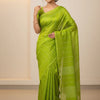 Woman wearing a bright green Indian saree with subtle silver stripes, posing in a neutral indoor setting