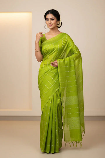 Woman wearing a bright green Indian saree with subtle silver stripes, posing in a neutral indoor setting